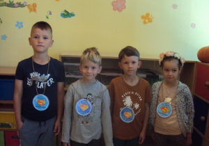 Chłopcy i dziewczynki prezentują swoje medale "Super chłopaka"
